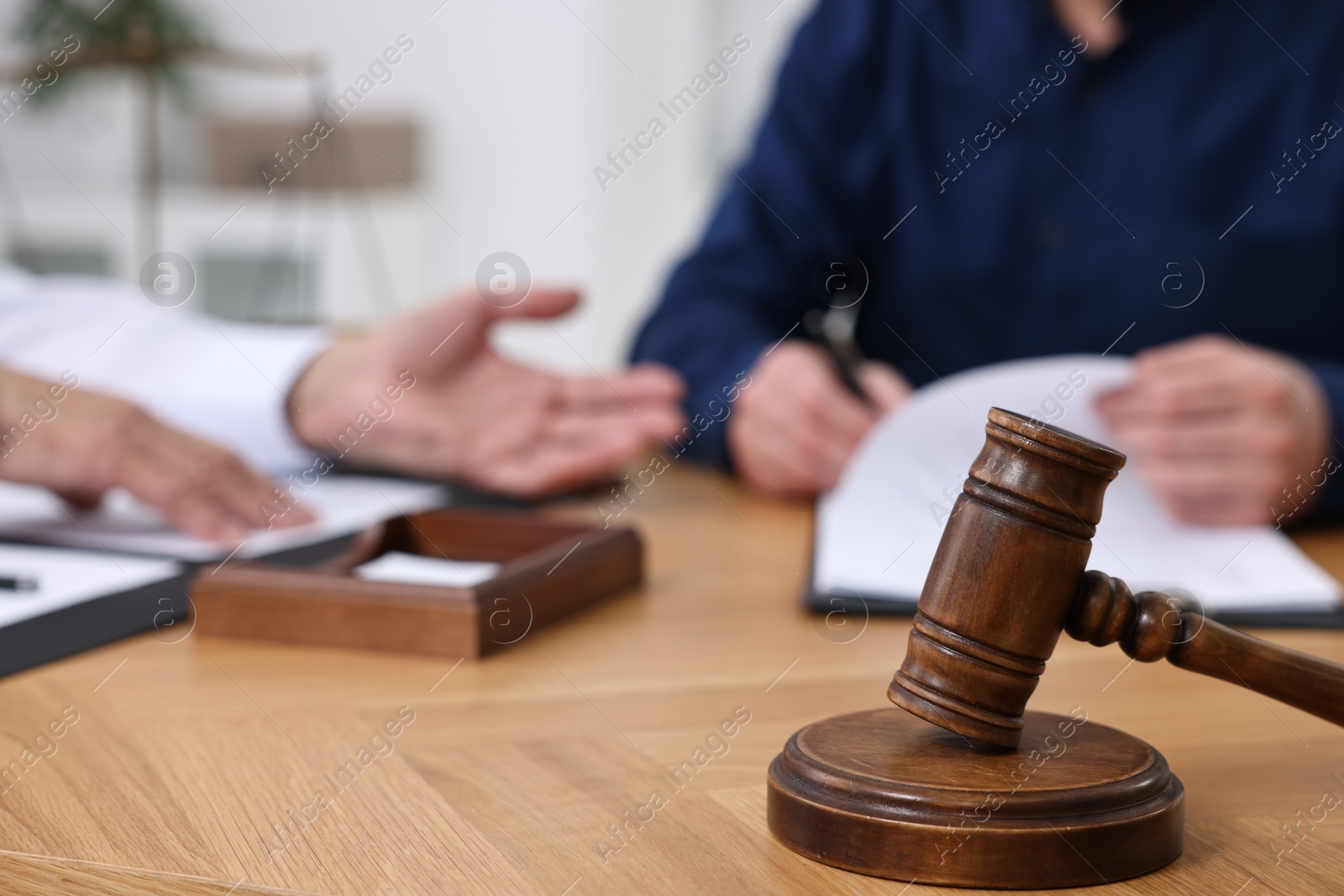 Photo of Man signing document in lawyer's office, focus on gavel