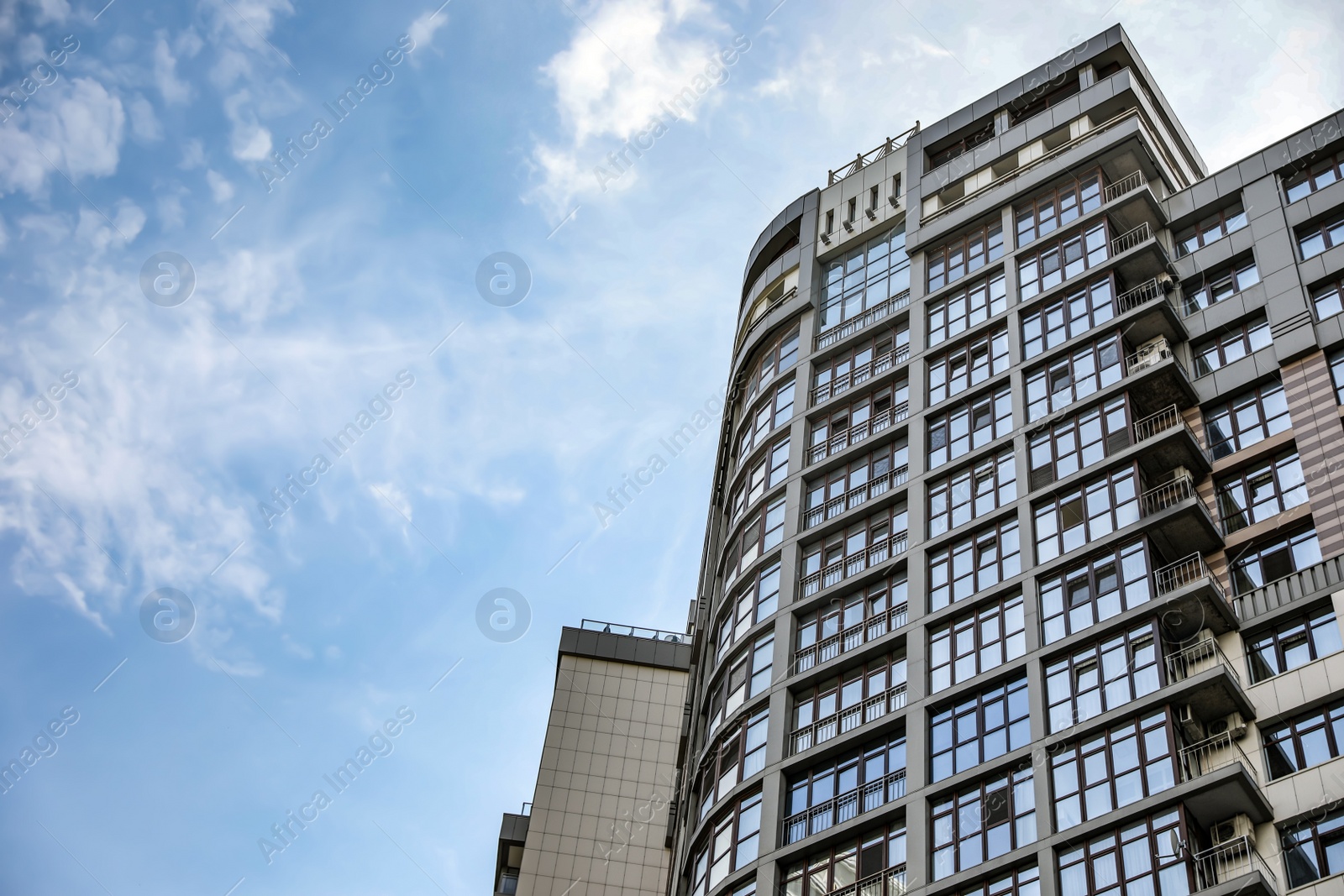 Photo of Modern building with tinted windows against sky, low angle view. Urban architecture