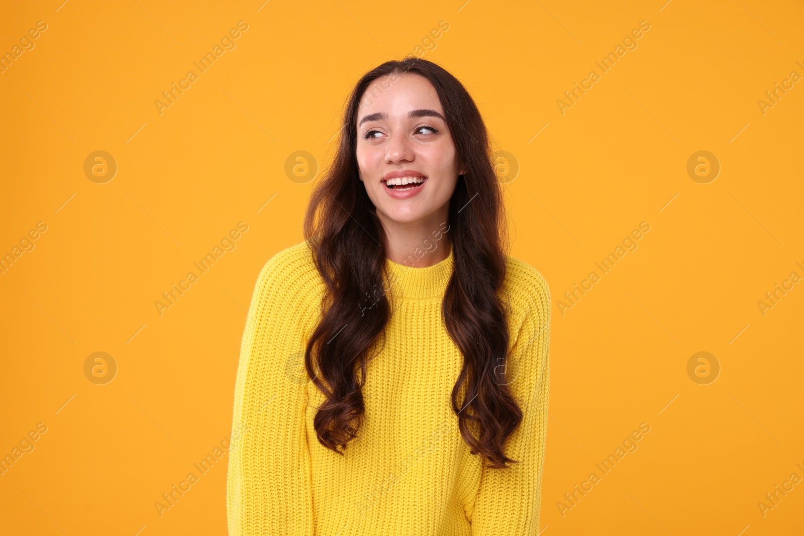 Photo of Beautiful young woman in stylish warm sweater on orange background