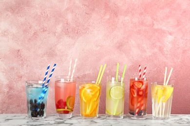 Photo of Glasses with lemonades on table against color background