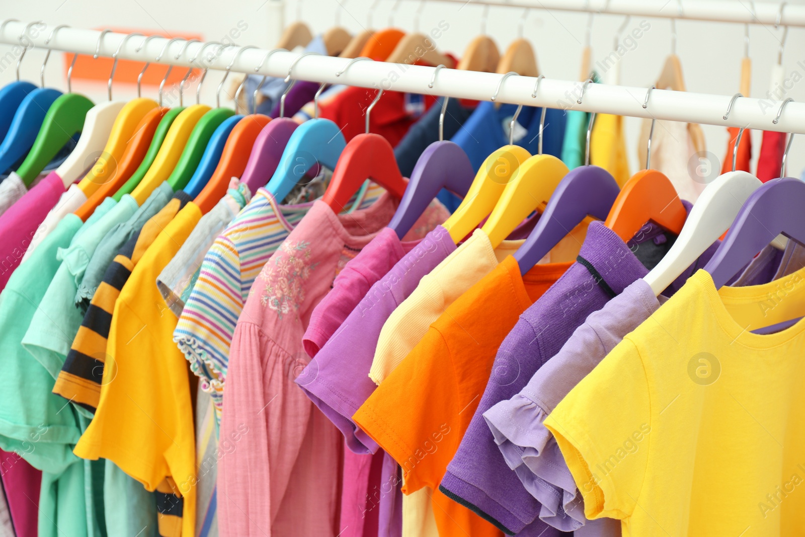 Photo of Different child's clothes hanging on rack indoors, closeup