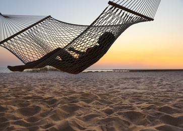 Photo of Young woman relaxing in hammock on beach