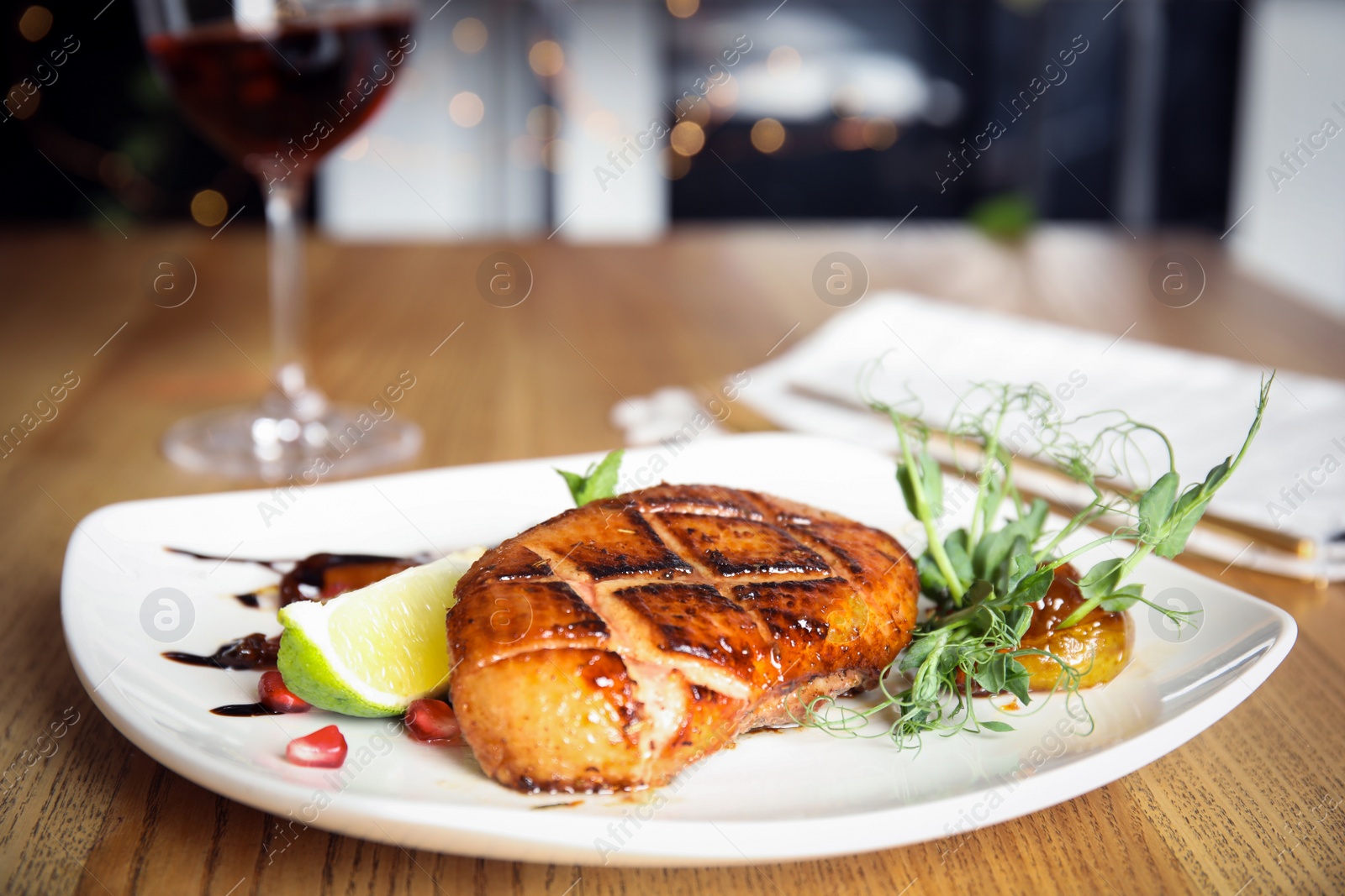 Photo of Delicious grilled duck breast served on wooden table indoors, closeup