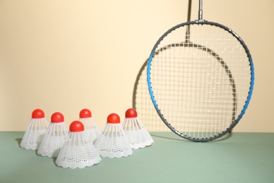 Shuttlecocks and racquet against beige background. Badminton equipment
