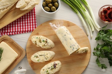 Photo of Tasty butter, bread and other ingredients on wooden table, flat lay