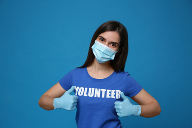 Photo of Female volunteer in mask and gloves on blue background. Protective measures during coronavirus quarantine