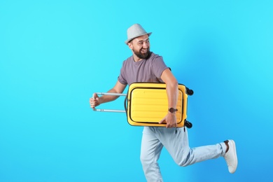 Photo of Man with suitcase running on color background. Vacation travel