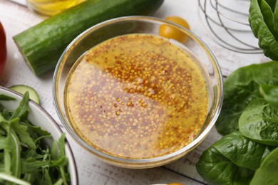 Photo of Tasty vinegar based sauce (Vinaigrette) in bowl and products on wooden rustic table, closeup