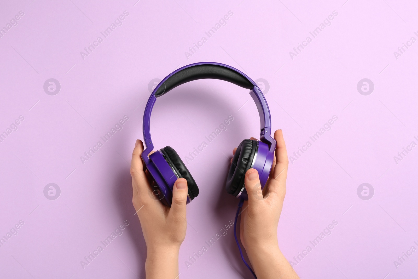 Photo of Woman holding stylish headphones on color background, closeup