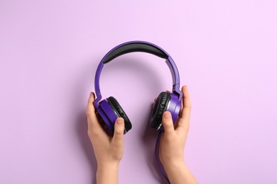 Woman holding stylish headphones on color background, closeup