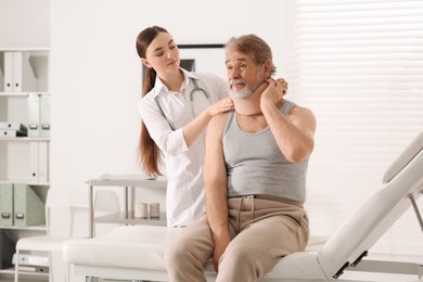 Orthopedist applying cervical collar onto patient's neck in clinic