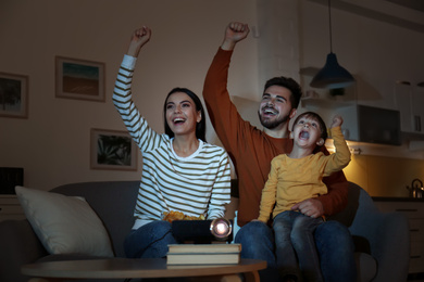 Photo of Emotional family watching TV using video projector at home
