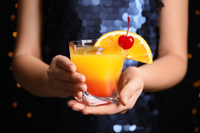 Woman with glass of Tequila Sunrise, closeup. Delicious alcoholic cocktail