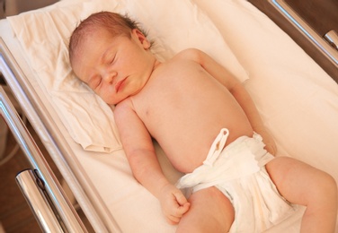 Photo of Newborn child sleeping on bed in hospital