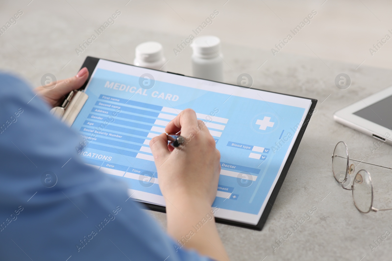 Photo of Doctor filling patient's medical card in clinic, closeup