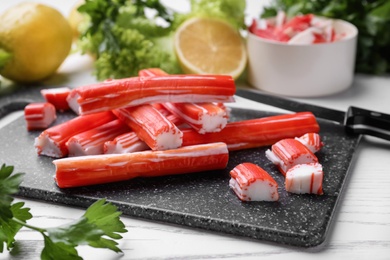 Photo of Delicious crab sticks on white wooden table, closeup