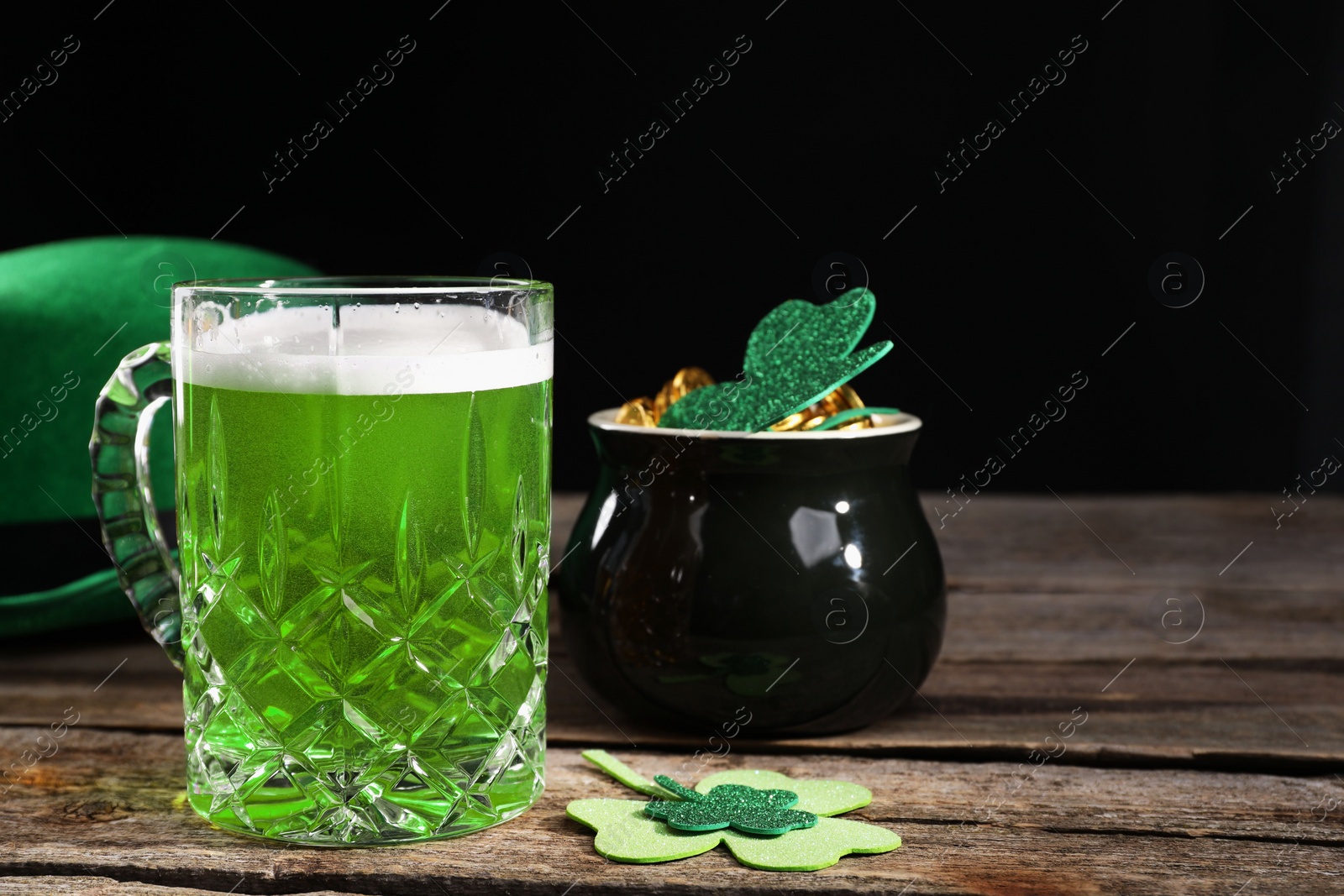 Photo of St. Patrick's day party. Green beer, leprechaun hat, pot of gold and decorative clover leaves on wooden table. Space for text