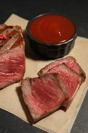 Photo of Delicious grilled beef steak with spices and tomato sauce on table