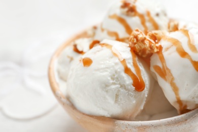 Tasty ice cream with caramel sauce and popcorn in bowl on table, closeup