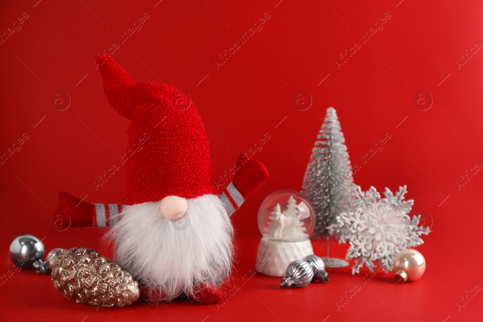 Photo of Cute Christmas gnome and festive decor on red background