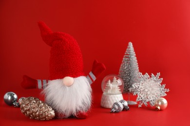 Photo of Cute Christmas gnome and festive decor on red background