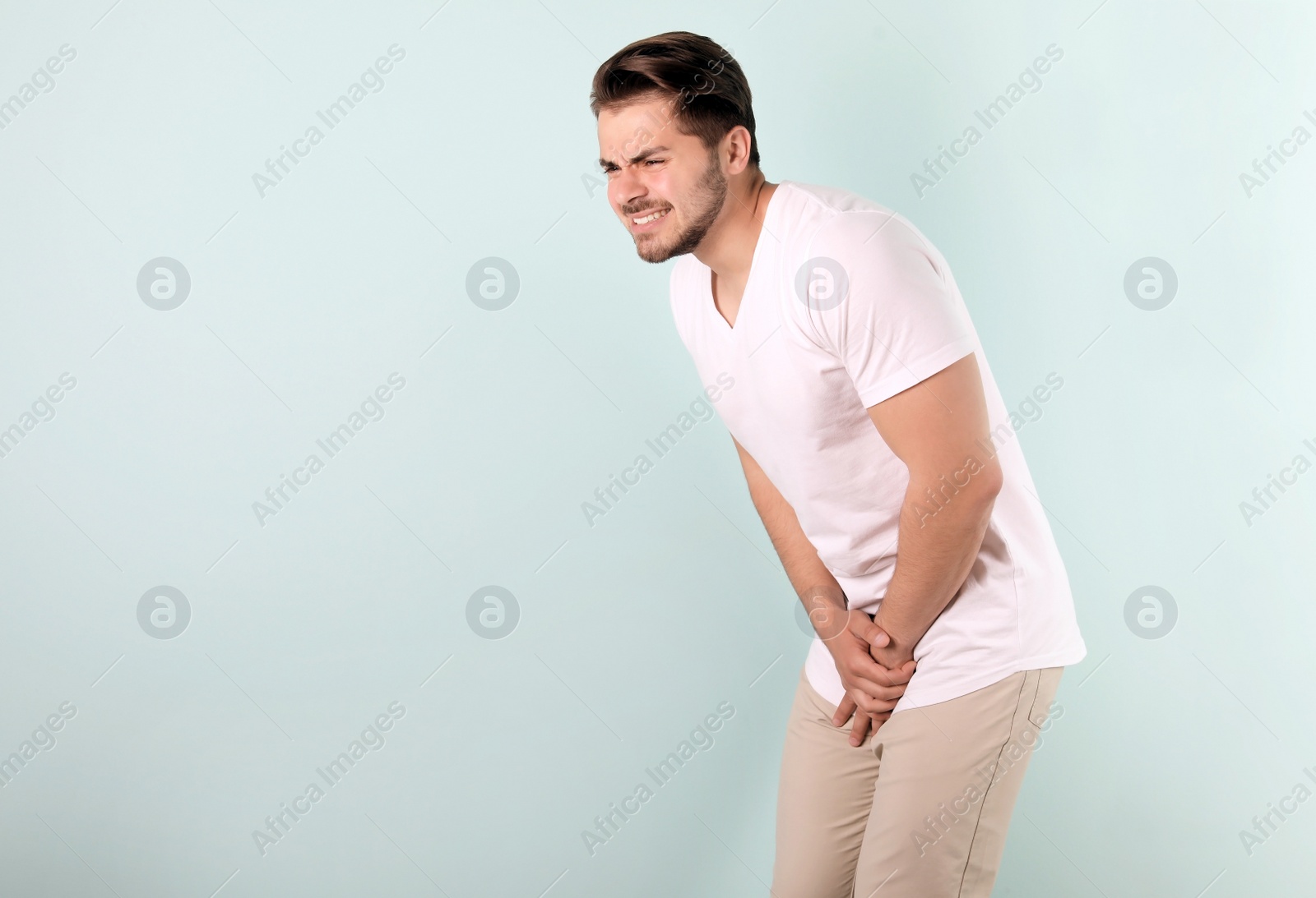 Photo of Young man with urological problems suffering from pain on color background