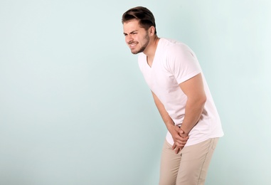 Photo of Young man with urological problems suffering from pain on color background