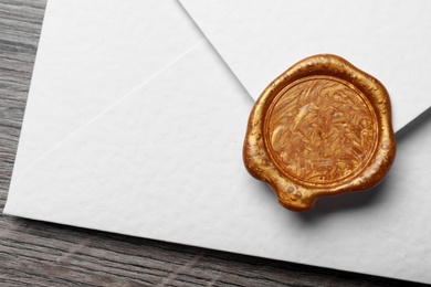 Photo of White envelope with wax seal on wooden background, closeup