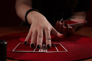 Photo of Soothsayer predicting future with cards at table indoors, closeup