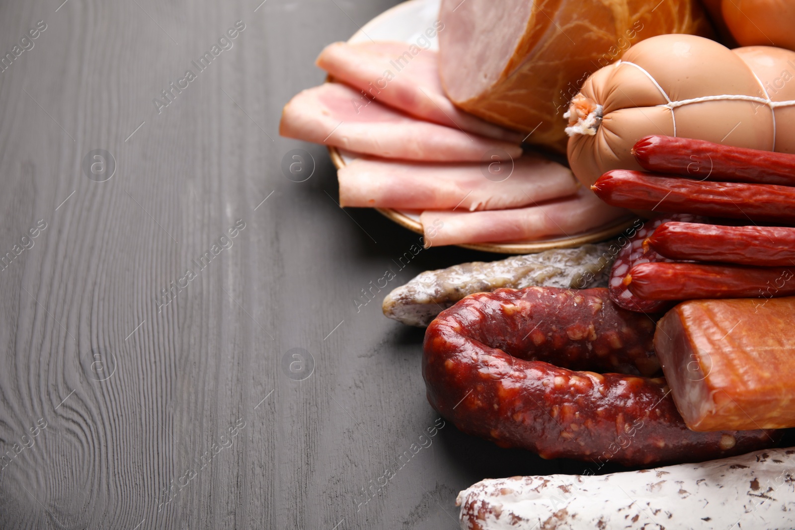 Photo of Different types of sausages on light grey wooden table, closeup. Space for text