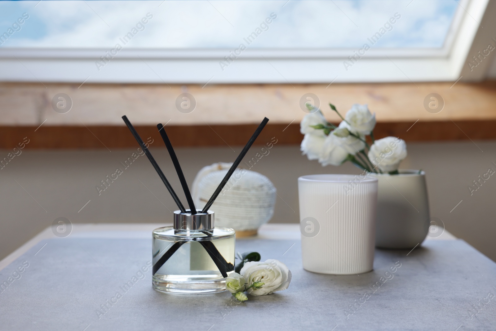 Photo of Reed diffuser, scented candle and eustoma flowers on gray marble table