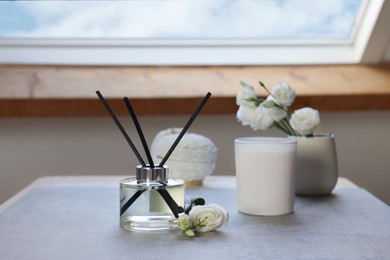 Reed diffuser, scented candle and eustoma flowers on gray marble table