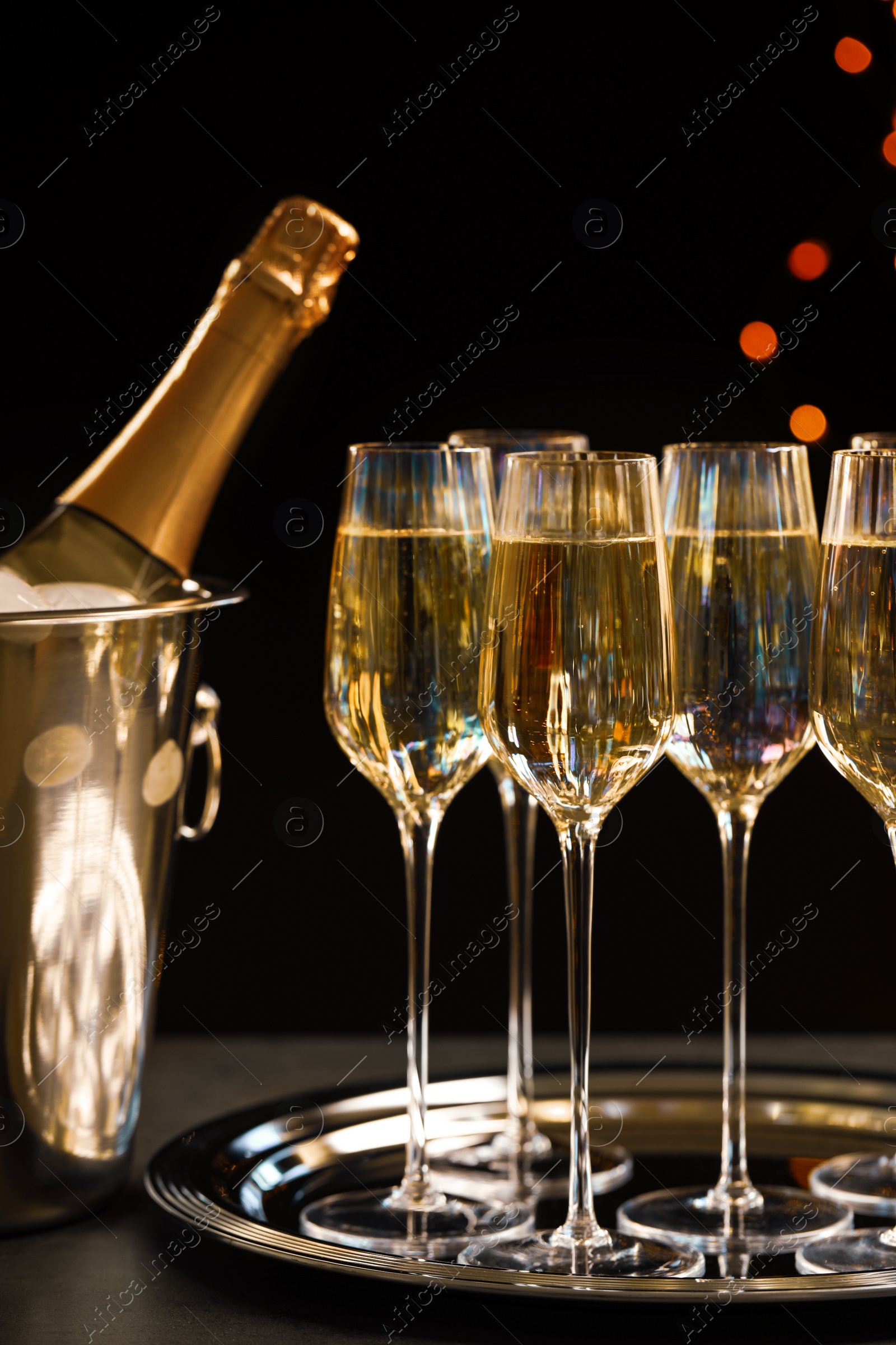 Photo of Glasses of champagne and ice bucket with bottle on grey table