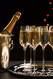 Glasses of champagne and ice bucket with bottle on grey table