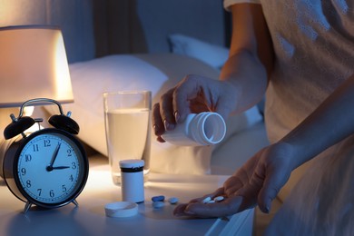 Photo of Woman with pills in bedroom at night, closeup. Insomnia concept