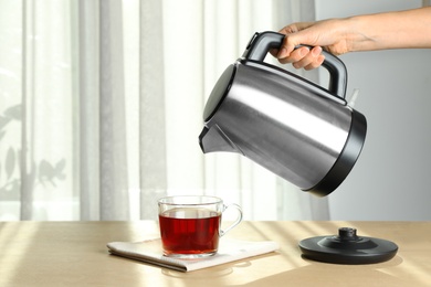 Woman making tea at wooden table indoors, closeup