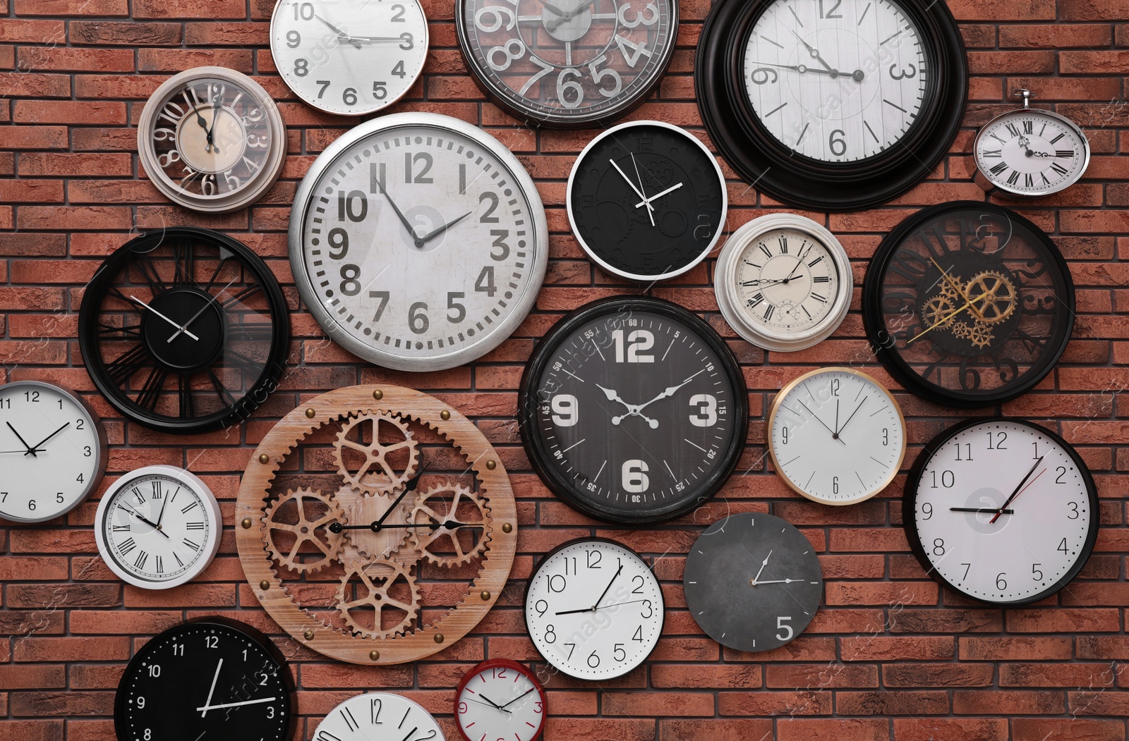 Photo of Collection of clocks hanging on red brick wall