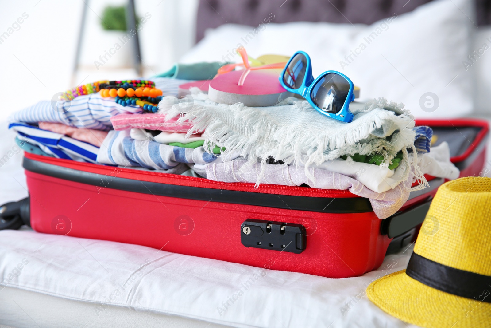 Photo of Open suitcase with different clothes and accessories for summer journey on bed