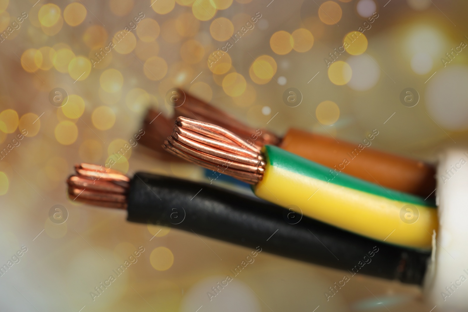 Image of Colorful electrical wires against golden background with blurred lights, closeup. Bokeh effect