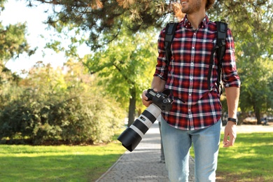 Photo of Young male photographer with professional camera in park. Space for text