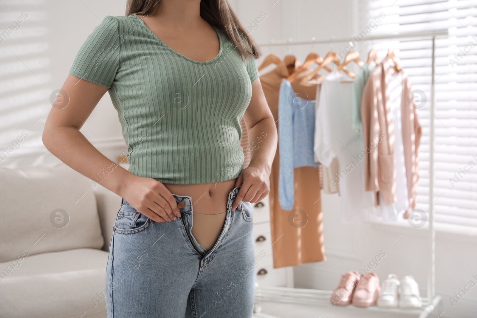 Photo of Woman trying to put on tight jeans at home, closeup. Space for text