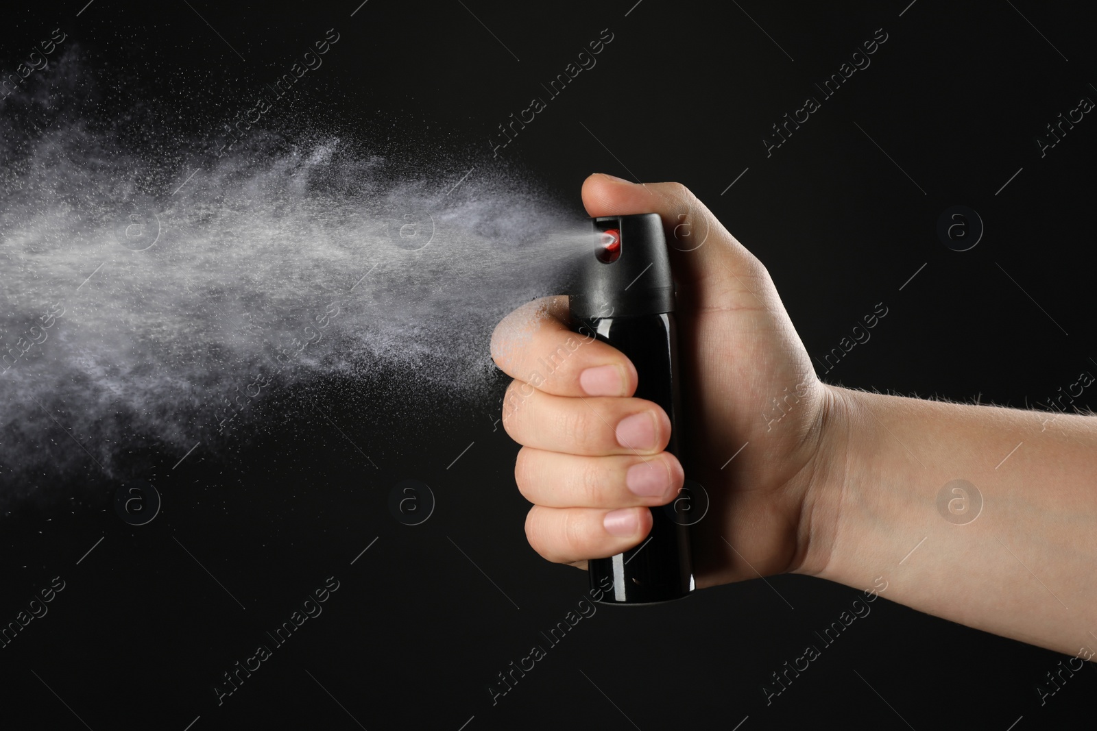 Image of Man using pepper spray on black background, closeup