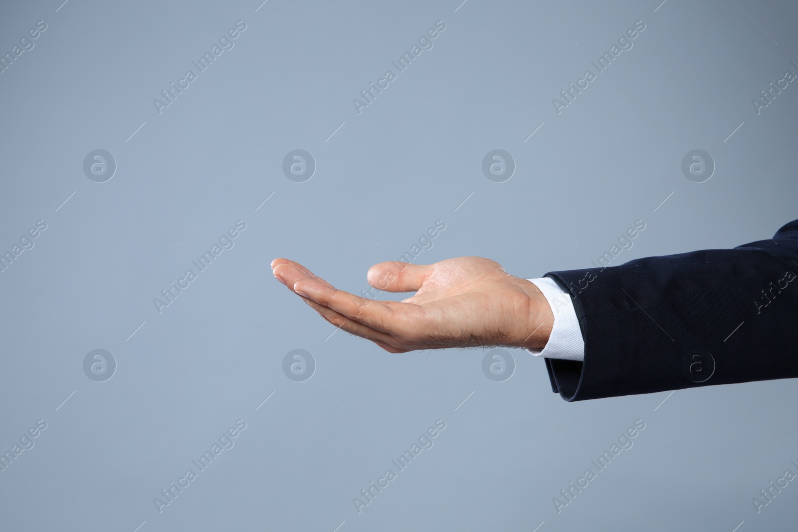 Photo of Businessman holding something on grey background, closeup view of hand with space for text