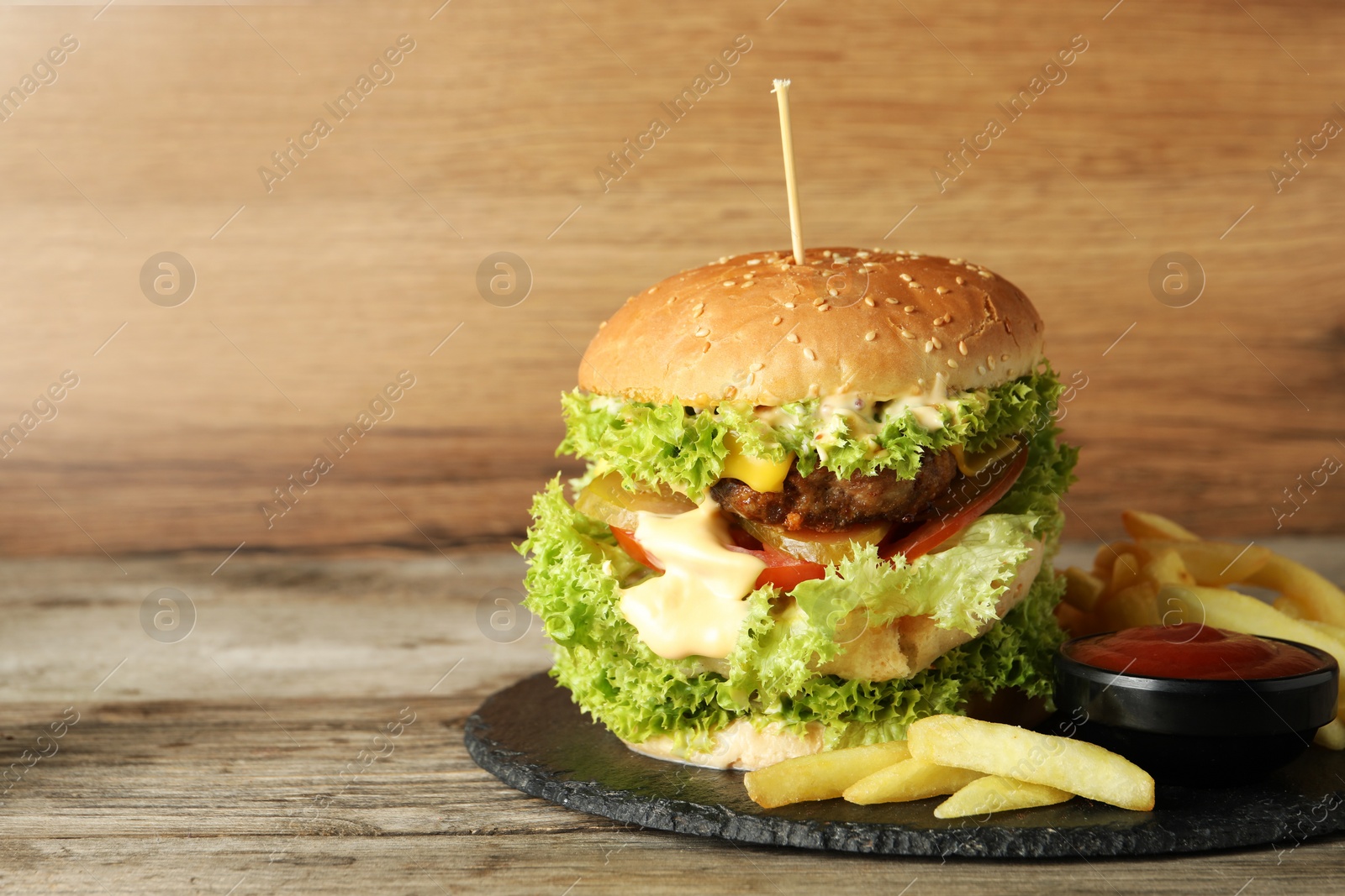 Burger with delicious patty, french fries and sauce on wooden table, space for text Photo of Burger with delicious patty, french fries and sauce on wooden table, space for text