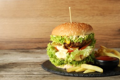 Photo of Burger with delicious patty, french fries and sauce on wooden table, space for text