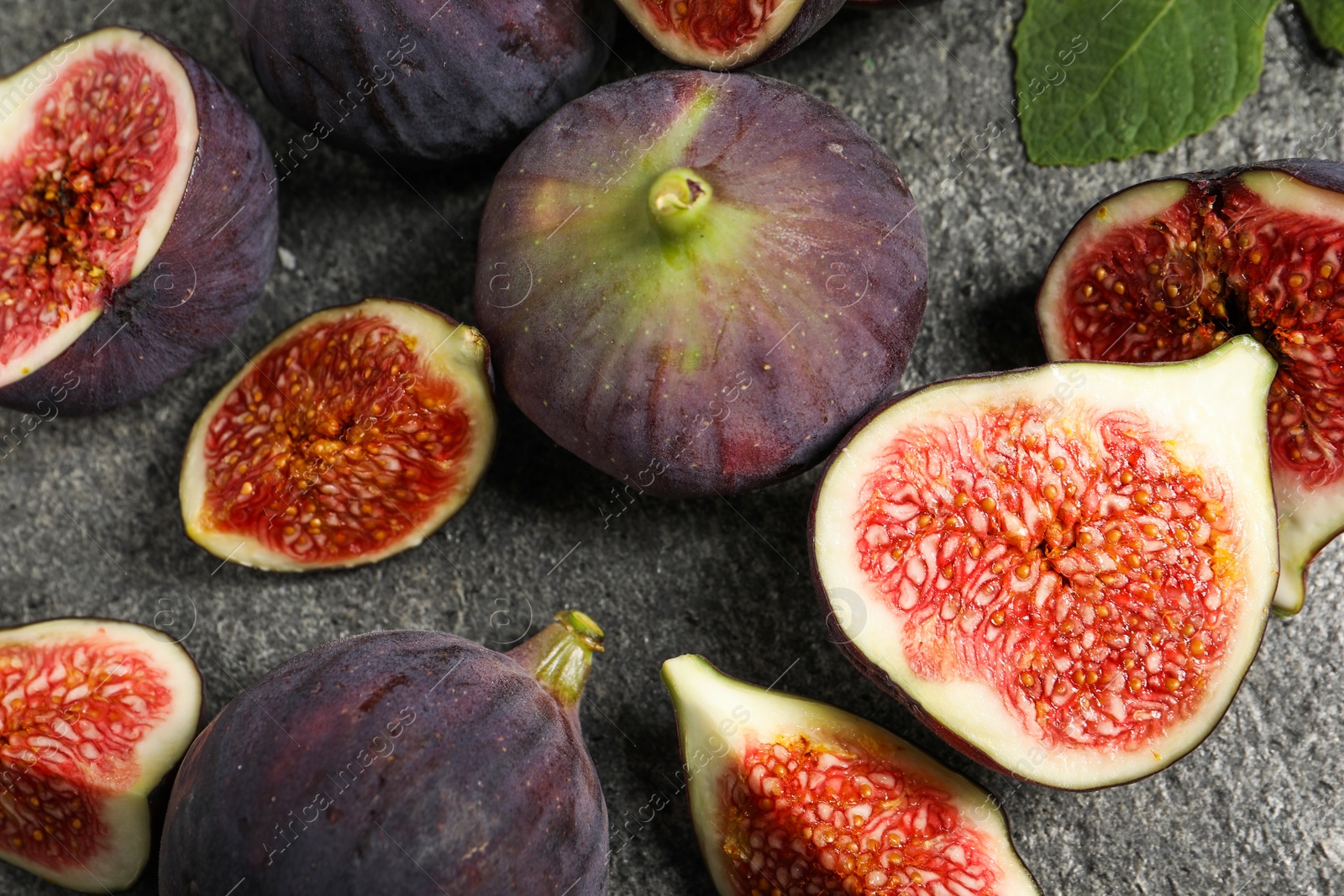 Photo of Whole and cut ripe figs on grey textured table, flat lay