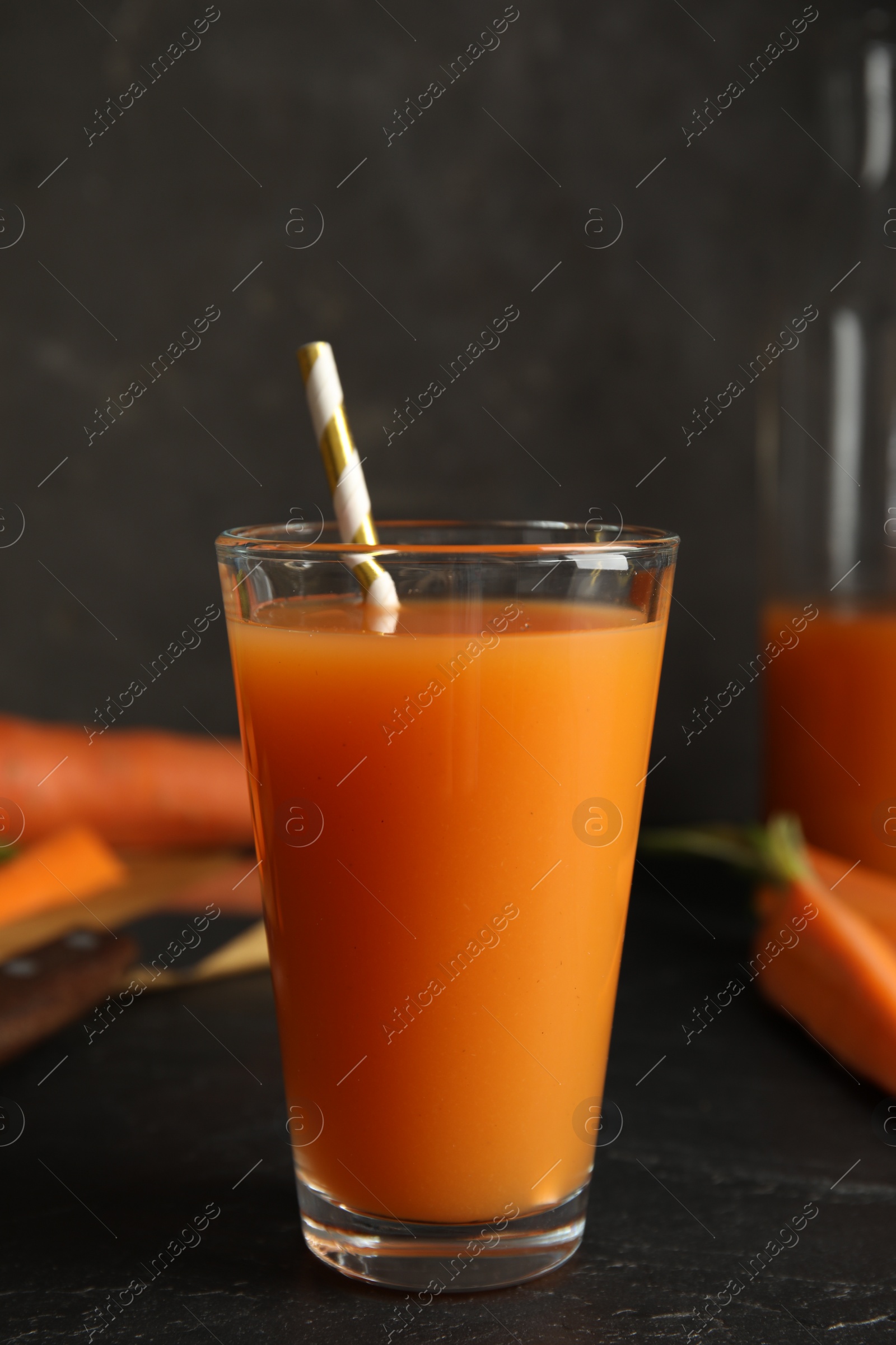 Photo of Glass of freshly made carrot juice on black table