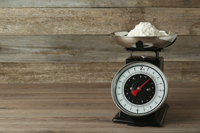 Photo of Kitchen scale with flour on wooden table. Space for text