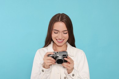 Young woman with camera on light blue background. Interesting hobby