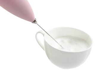 Photo of Whisking milk in cup with mini mixer (frother wand) isolated on white, closeup